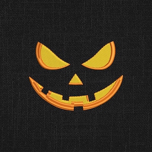 Puede incluir: Bordado de una cara de calabaza de Halloween con hilo naranja y amarillo sobre un fondo negro. El diseño presenta ojos triangulares, una nariz triangular y una boca sonriente y dentada. La textura de la tela es visible.