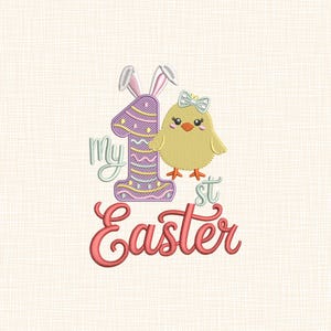 Könnte beinhalten: Gesticktes Design mit einem gelben Küken mit blauer Schleife, einer lila Eins mit Hasenohren und den Worten "My 1st Easter" in Schreibschrift. Das Design befindet sich auf einem cremefarbenen Hintergrund.