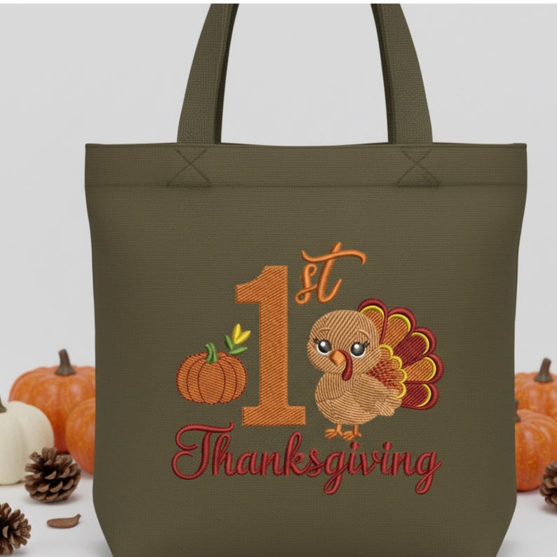 May include: An olive green tote bag featuring an embroidered design with a large orange number 1, the text "st" and "Thanksgiving" in red, a small orange pumpkin, and a cartoon turkey with brown, yellow, and red feathers on the front.