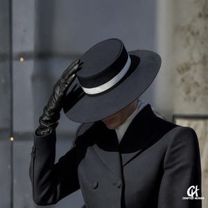 Elegant black felt top hat with wide brim and white satin band, inspired by Melania Trump’s inauguration style, displayed on white background