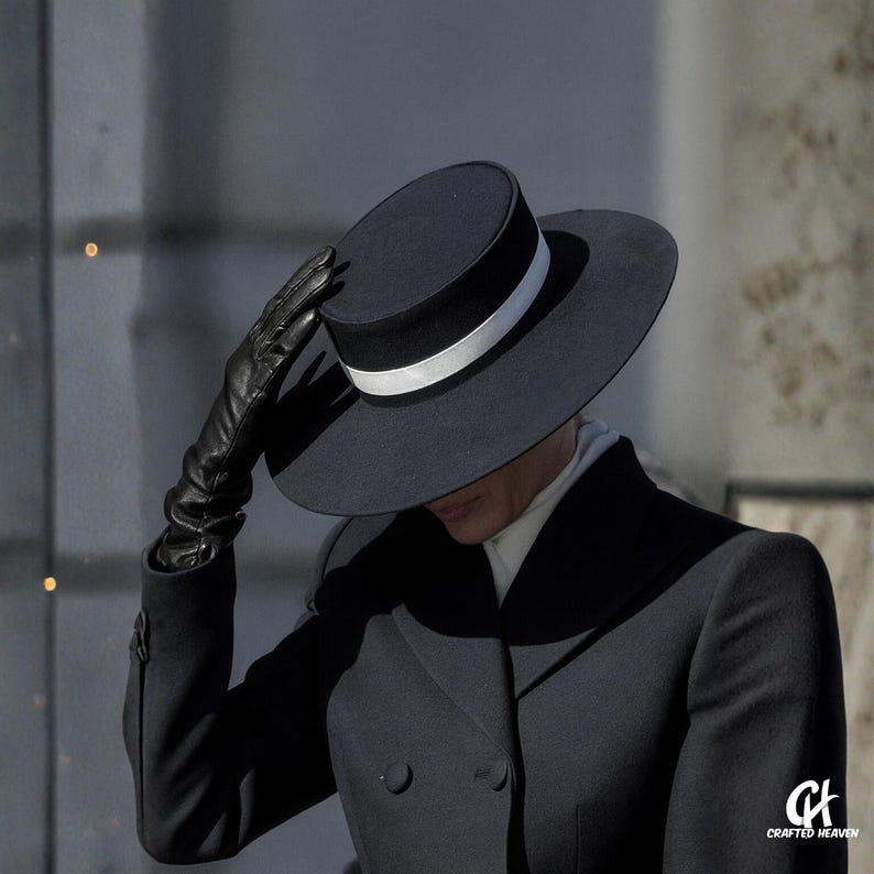 Elegant black felt top hat with wide brim and white satin band, inspired by Melania Trump’s inauguration style, displayed on white background