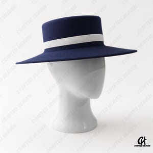 Elegant black felt top hat with wide brim and white satin band, inspired by Melania Trump’s inauguration style, displayed on white background