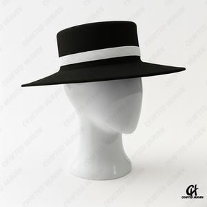 Elegant black felt top hat with wide brim and white satin band, inspired by Melania Trump’s inauguration style, displayed on white background
