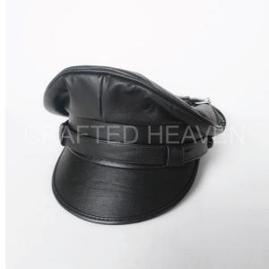 May include: A black leather officer's cap with a silver buckle and a wide brim.