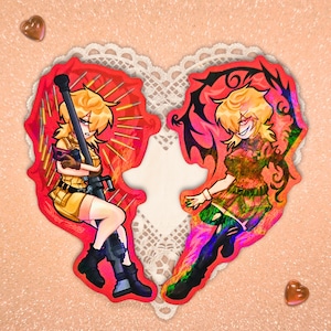 May include: Two heart-shaped stickers featuring anime-style characters. One character is in a military uniform holding a weapon, the other has a demonic appearance. The stickers are red with holographic accents, set against a peach background with lace.