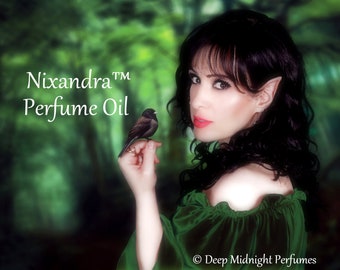 May include: A woman with long dark hair and pointed ears holds a small black bird in her hand. The background is a blurred green forest. The text "Nixandra™ Perfume Oil" is written in white on a green background. The text "© Deep Midnight Perfumes" is written in white on a black background at the bottom of the image.