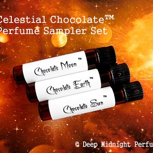 Op de afbeelding: Drie kleine glazen flesjes met zwarte dopjes en witte etiketten. De etiketten hebben de tekst "Chocolate Moon", "Chocolate Earth" en "Chocolate Sun" erop. De flesjes zijn gestapeld op een achtergrond van een sterrenstelsel met sterren en planeten.