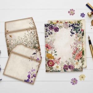 May include: Vintage-style stationery set with floral designs. Includes two envelopes, a lined paper sheet with a floral border, a gold pen, inkwell, wax seal, and dried flowers. The envelopes and paper have a distressed, aged appearance.