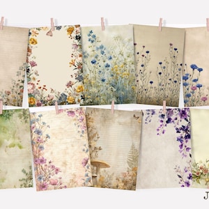 May include: A collection of ten vintage-style paper prints, each adorned with floral and botanical illustrations. The prints are in various shades of beige and cream, with colorful flowers and greenery. The prints are hung with pink clothespins.