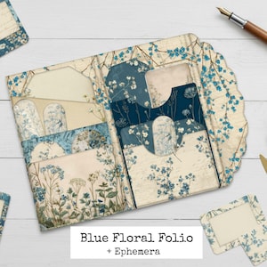 May include: A blue floral folio with ephemera, featuring a scalloped edge and multiple pockets. The design includes blue floral patterns on a cream background. Additional stationery items and a pen are also visible.