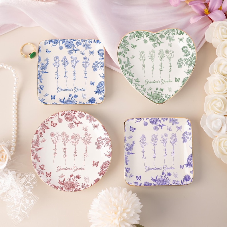 Pu&ograve; includere: Quattro piatti decorativi in ceramica di varie forme: quadrato, cuore, rotondo e quadrato. Ogni piatto presenta disegni floreali in blu, verde, rosso e viola, con bordi dorati. Il testo "Grandma's Garden" &egrave; stampato su ogni piatto.