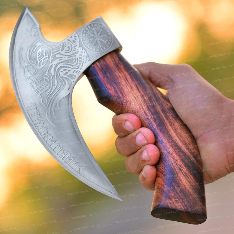 May include: A silver axe with a wooden handle. The axe head has intricate engravings and the text "MARS" in a stylized font. The handle is dark brown wood with a smooth finish.