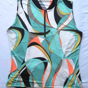 May include: Sleeveless shirt with a black collar and a zip fastening. The shirt has a white background with a colourful abstract pattern in shades of teal, orange, black, and gold.