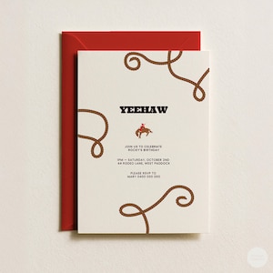 Può includere: Un biglietto d'invito di compleanno color crema con una busta rossa. Il biglietto presenta illustrazioni di corde marroni negli angoli, il testo YEEHAW, una piccola grafica di una persona a cavallo e i dettagli per il compleanno di Rocky il 2 ottobre.