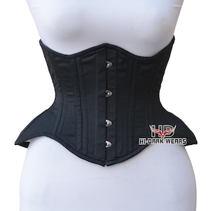 May include: A black corset featuring a structured design with vertical paneling and a front closure consisting of four silver-toned metal busk clasps. The garment displays the text HI-DARK WEARS with a red and white wing logo on the lower right side.