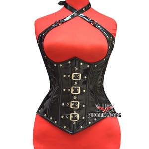 May include: Black patent leather corset with a halter neck and multiple buckles. The corset features a structured bodice with decorative rivets and a logo on the side. The garment is displayed on a red mannequin.