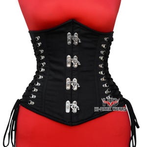 May include: Black corset with silver clasps and eyelets, displayed on a red mannequin. The corset has a structured design with a pointed front and is laced up on the sides. The text "HI-DARK WEARS" is visible on the lower right side.