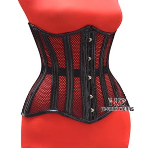 Può includere: Corsetto nero con interno in rete rossa. Il corsetto presenta pannelli neri verticali e un davanti nero lucido con chiusure argentate. Il testo "HI-DARK WEARS" è visibile in basso a destra.