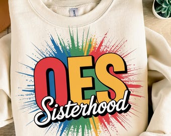 May include: Cream-colored sweatshirt with the text "OES Sisterhood" in a colorful, eye-catching design. The letters "OES" are in red and yellow, with a burst of rainbow colors behind them. A casual, comfortable top.