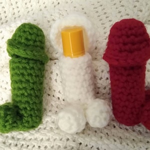 May include: Three crocheted covers for lip balm tubes. The covers are green, white, and red. The white cover has a yellow lip balm tube inside.