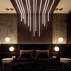 Può includere: Una camera da letto moderna con una testata nera e una parete a listelli di legno scuro dietro. Il soffitto ha un design unico con listelli di legno e illuminazione incassata. Ci sono tre luci a sospensione a forma di globo che pendono sopra il letto.