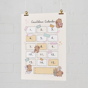 Op de afbeelding: Een beige aftelkalender met de tekst "Countdown Calendar" en de nummers 1-15. De kalender bevat schattige berenillustraties en decoratieve elementen zoals washi tape en potloden. De kalender hangt aan een muur.