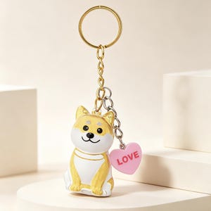 May include: A gold-colored metal keychain featuring a Shiba Inu dog figurine with a white belly and a pink heart charm that says "LOVE". The keychain has a gold ring and chain.