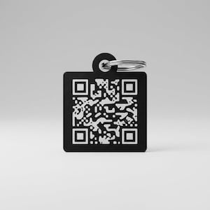 Könnte beinhalten: Ein quadratischer schwarzer Haustieranhänger aus Metall mit einem weißen QR-Code-Muster auf der Vorderseite. Der Anhänger hat eine kreisförmige Öse an der Oberseite, an der ein silberfarbener Metallring zur Befestigung am Halsband angebracht ist.