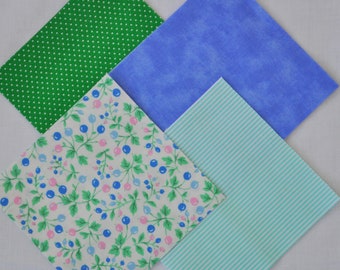May include: Four square fabric swatches in a diamond arrangement. The fabrics feature various patterns: green polka dots, blue mottled, floral with berries, and light blue stripes. The fabrics are likely for quilting or crafting.