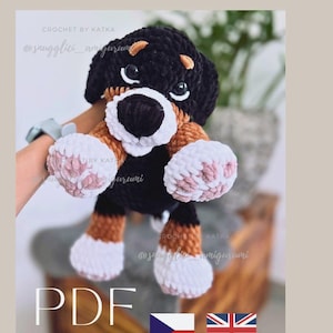 May include: A handmade crochet dog amigurumi in black, brown, and white. The plush toy has a round head, floppy ears, and a white muzzle. The text "PDF" is visible, along with the shop's name and social media handle.