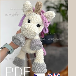 May include: A handmade, plush unicorn amigurumi in cream, gray, and lavender. The crochet unicorn has a fluffy mane, a brown horn, and gray hooves. The text "PDF" is visible, along with the seller's name.