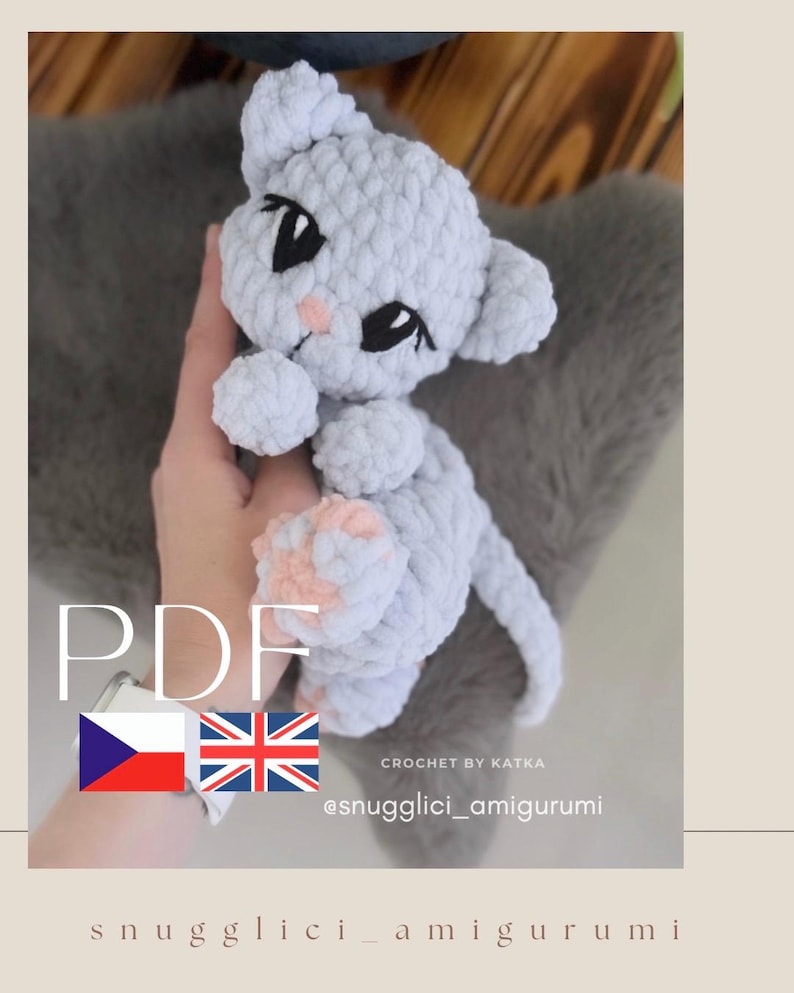 May include: A light gray crocheted cat amigurumi with black eyes and pink accents. The handmade plush toy has a fluffy texture and is shown against a blurred background. The word "PDF" is visible, along with the text "CROCHET BY KATKA" and the Instagram handle @snugglici_amigurumi.
