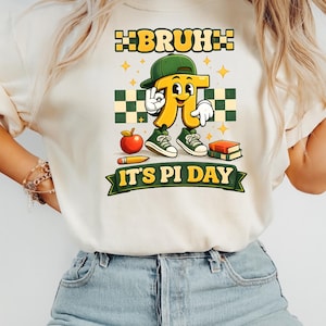 May include: Cream-colored t-shirt with a graphic featuring a cartoon pi symbol wearing a green cap and sneakers. The shirt has the text "BRUH" above and "IT'S PI DAY" below the pi symbol, along with an apple, pencil, and books.