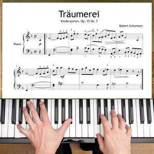 Puede incluir: Un teclado de piano con teclas negras y blancas. La partitura de "Träumerei" de Robert Schumann es visible encima de las teclas. La notación musical incluye claves de sol y de fa, notas e indicaciones dinámicas. Unas manos tocan el piano.
