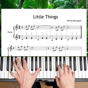 Puede incluir: Un teclado de piano con una partitura titulada "Little Things" de Adrián Berenguer. La partitura está colocada encima de las teclas del piano. La imagen muestra las manos de una persona tocando el piano.