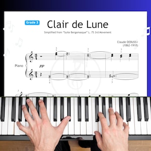 Può includere: Spartito di "Clair de Lune" di Claude Debussy, semplificato per pianoforte di 3° grado. L'immagine mostra lo spartito con le mani di una persona che suona i tasti del pianoforte. I tasti del pianoforte sono bianchi e neri.