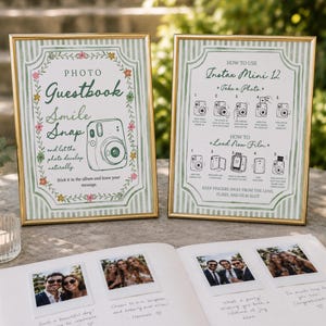 May include: Two gold-framed signs with green striped borders and floral accents. One sign reads Photo Guestbook Smile Snap, the other provides instructions for an Instax Mini 12 camera. An open photo album with four square photos sits in front.