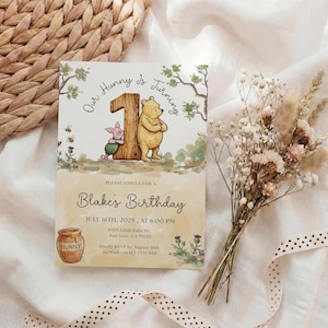 Watercolor illustration of a classic Winnie the Pooh and Piglet standing by a large wooden number one, featuring a honey pot, bees, and thistles on a soft yellow wash background.