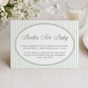 May include: A rectangular card featuring a light green and white vertical striped pattern. The centre displays an oval frame enclosing the text Books For Baby, with a request to bring a book instead of a card and to write a message inside.