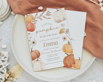 May include: Baby shower invitation with a pumpkin theme. The invitation features watercolor pumpkins in shades of orange, peach, and white, along with floral accents. The text reads "A Little Pumpkin is on the Way!" and includes the name "Emma" and event details.