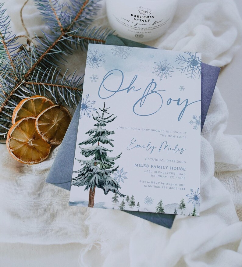 “Oh Boy” winter baby shower invitation with watercolor pine trees, delicate blue snowflakes, and elegant script text on a frosty blue background.