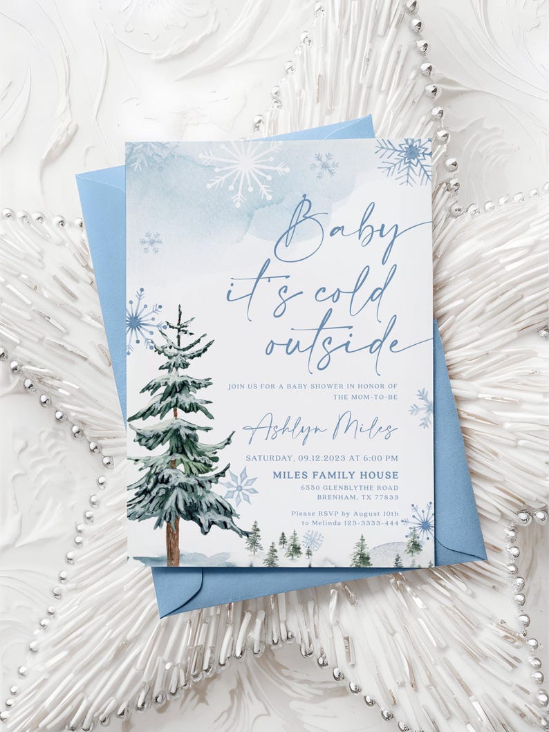 “Baby It’s Cold Outside” baby shower invitation with watercolor pine trees, scattered snowflakes, and elegant script on a soft winter background.