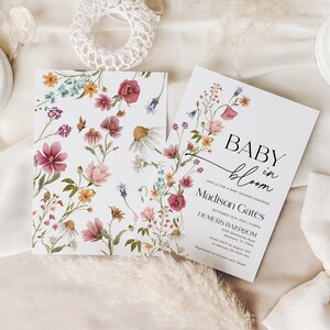 Editable “Baby in Bloom” baby shower invitation template featuring a soft watercolor wildflower border in blush, burgundy, yellow, and lavender, with elegant serif and script fonts on a white background, customizable via Templett