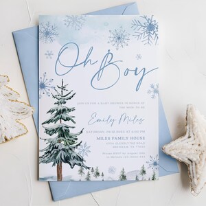 “Oh Boy” winter baby shower invitation with watercolor pine trees, delicate blue snowflakes, and elegant script text on a frosty blue background.