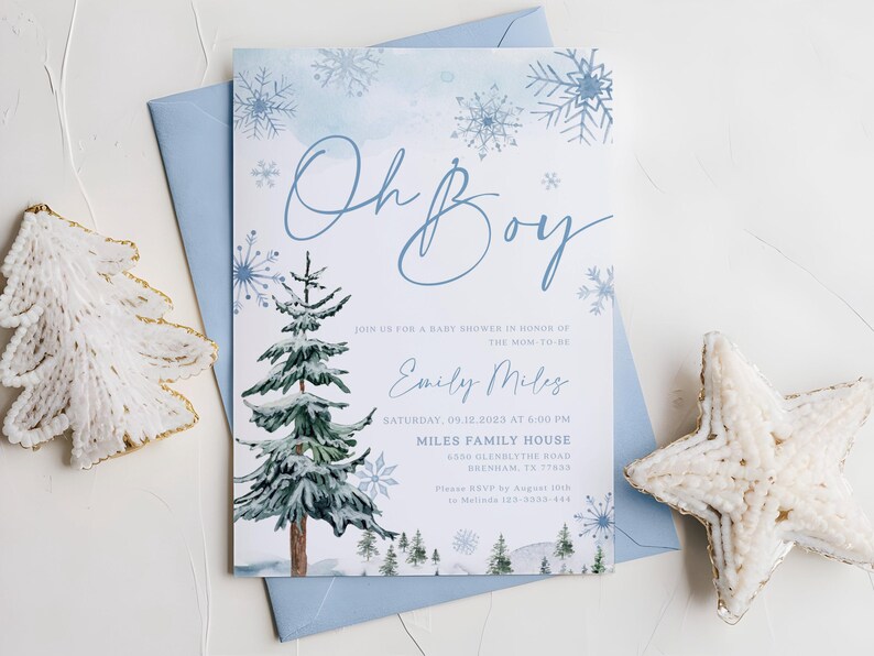 “Oh Boy” winter baby shower invitation with watercolor pine trees, delicate blue snowflakes, and elegant script text on a frosty blue background.