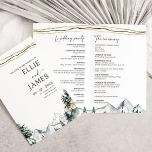 May include: Wedding program with gold and black detailing. The white program features the names Ellie and James, and the date 09.12.2023. The design includes a mountain and tree illustration.