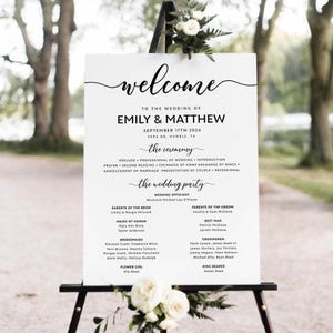 May include: A white wedding welcome sign with black text. The sign includes the names Emily & Matthew, the wedding date September 17th 2024, and the location Vera Dr. Humble, TX. The sign also lists the wedding ceremony details and the names of the wedding party.