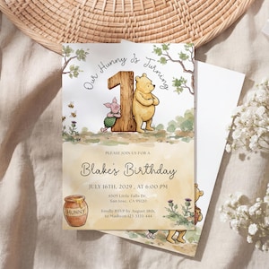 Watercolor illustration of a classic Winnie the Pooh and Piglet standing by a large wooden number one, featuring a honey pot, bees, and thistles on a soft yellow wash background.