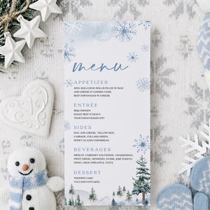 Puede incluir: Una tarjeta de menú con temática invernal con una ilustración de acuarela de un bosque nevado. El menú enumera aperitivos, entrantes, guarniciones, bebidas y postres. También se ven copos de nieve decorativos y un muñeco de nieve.