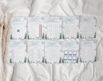May include: A set of ten bridal shower game cards featuring a winter theme with blue snowflakes and green pine trees. The cards include titles like Bridal Bingo, She Said He Said, Would She Rather, How Well Do You Know the Bride to Be, and Word Scramble.